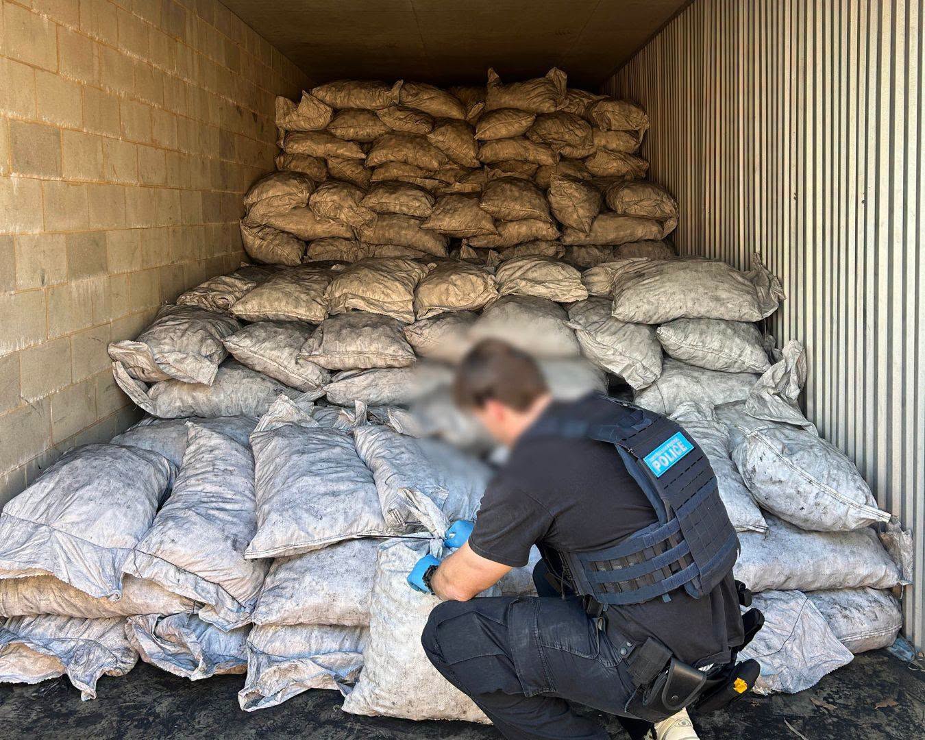 Law enforcement officer inspecting seized narcotics linked to international drug trafficking routes involving Ghana.