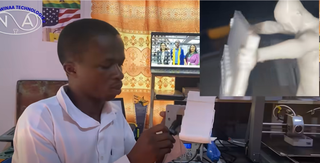 Young Ghanaian developer presenting a humanoid-inspired AI smartphone stand prototype designed to respond interactively to users