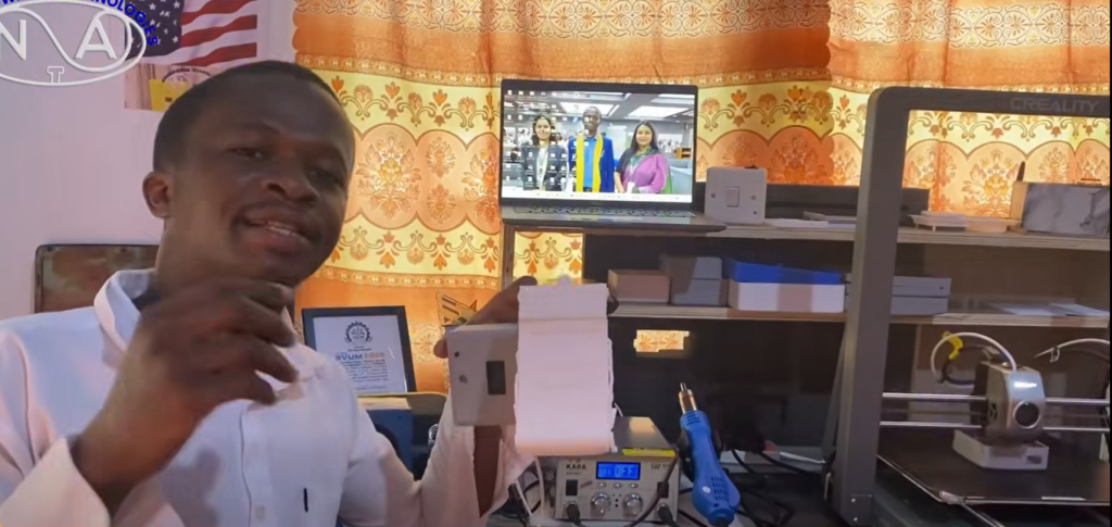Young Ghanaian developer presenting a humanoid-inspired AI smartphone stand prototype designed to respond interactively to users