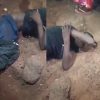 One of the suspected armed robbers lying on the floor, surrounded by residents, after being severely injured when iron rods protruding from a nearby building pierced his body